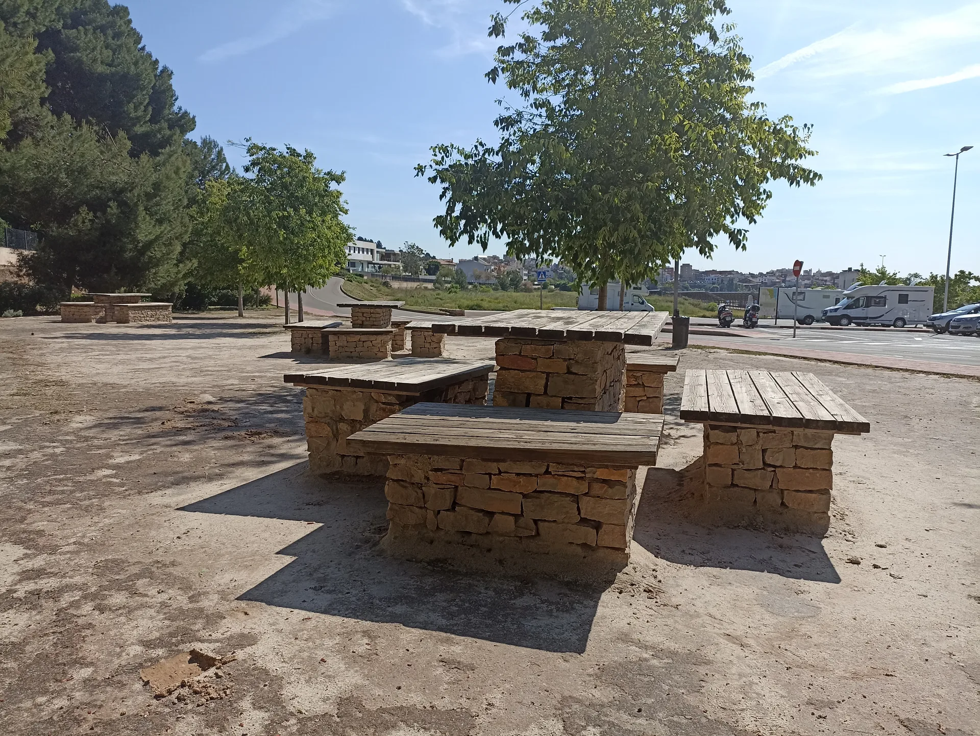 Área exterior con mesas de picnic junto a zona de aparcamiento/campers.