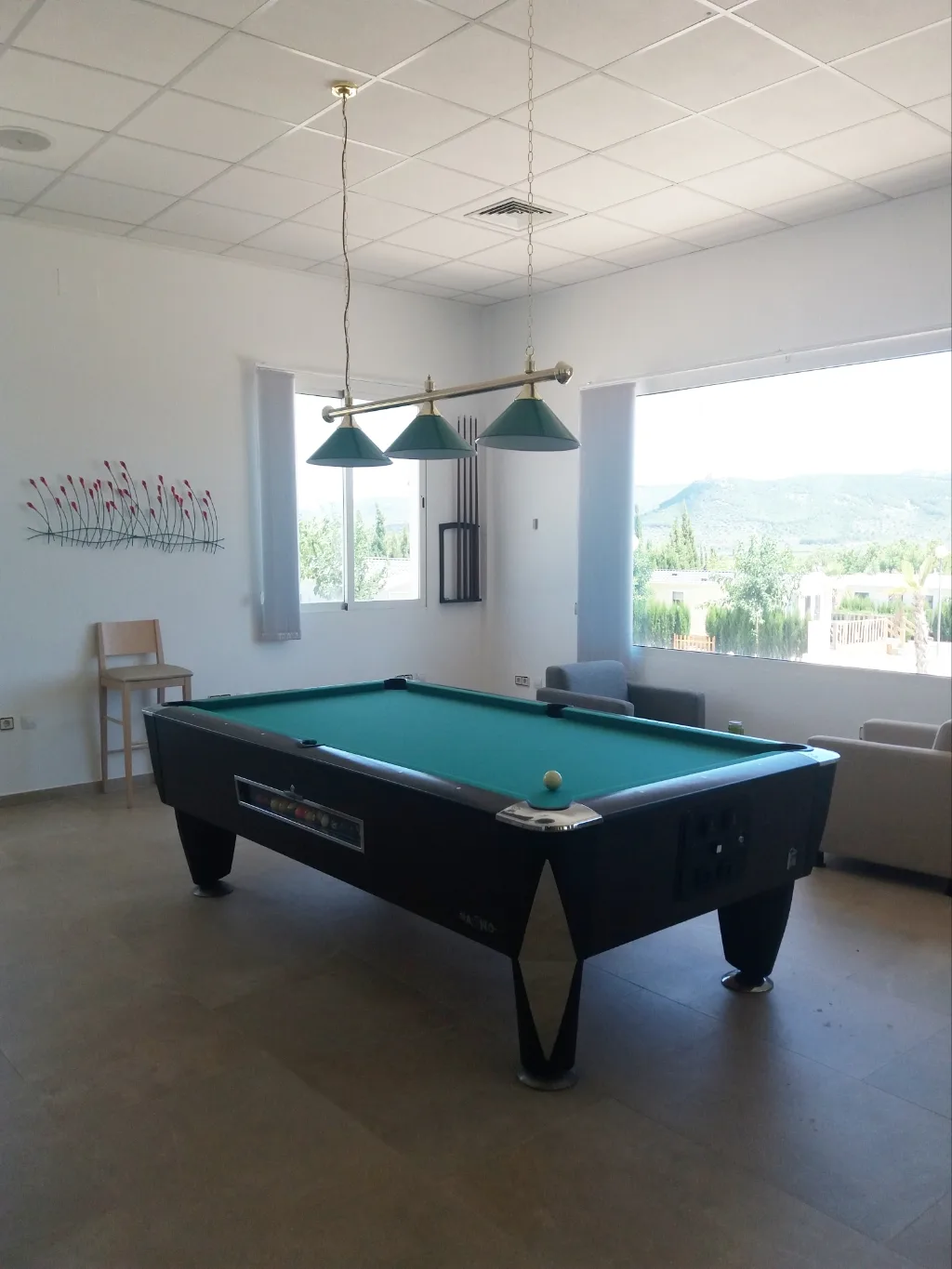 Sala interior con mesa de billar y vistas al exterior del camping.