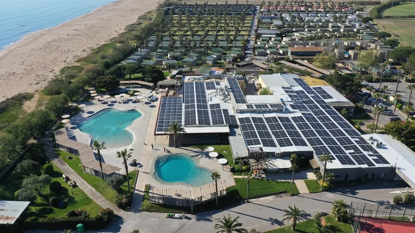 Vista aérea del camping con piscinas, edificios y parcelas junto a la playa.