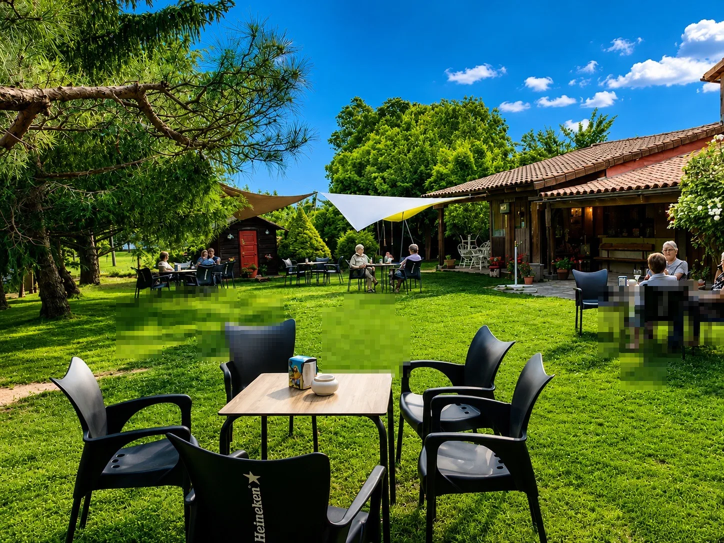 Terraza ajardinada del camping/bar con mesas y sillas al aire libre.