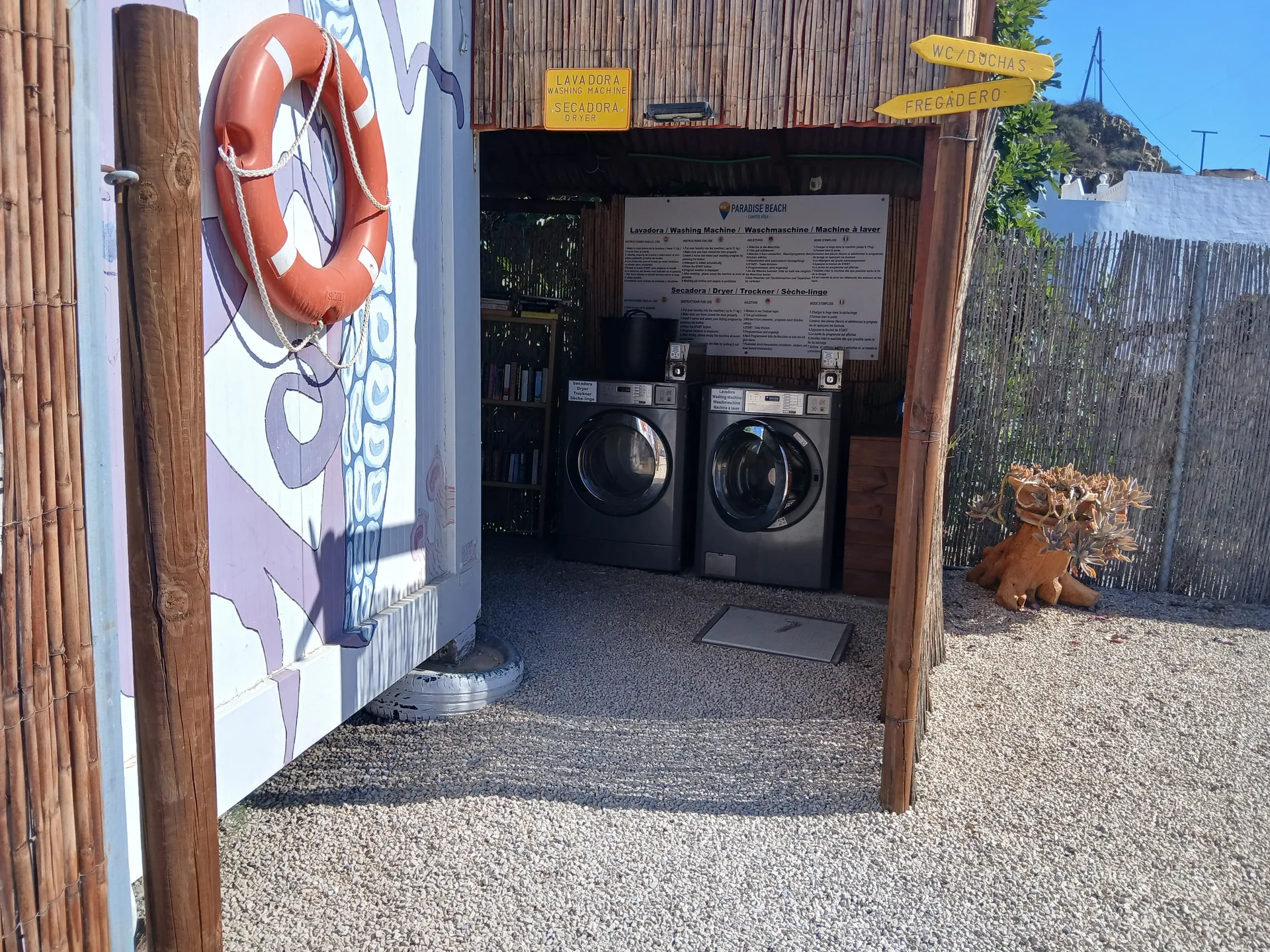 Zona de lavandería del área, con lavadora, secadora y señales de WC/duchas y fregadero.