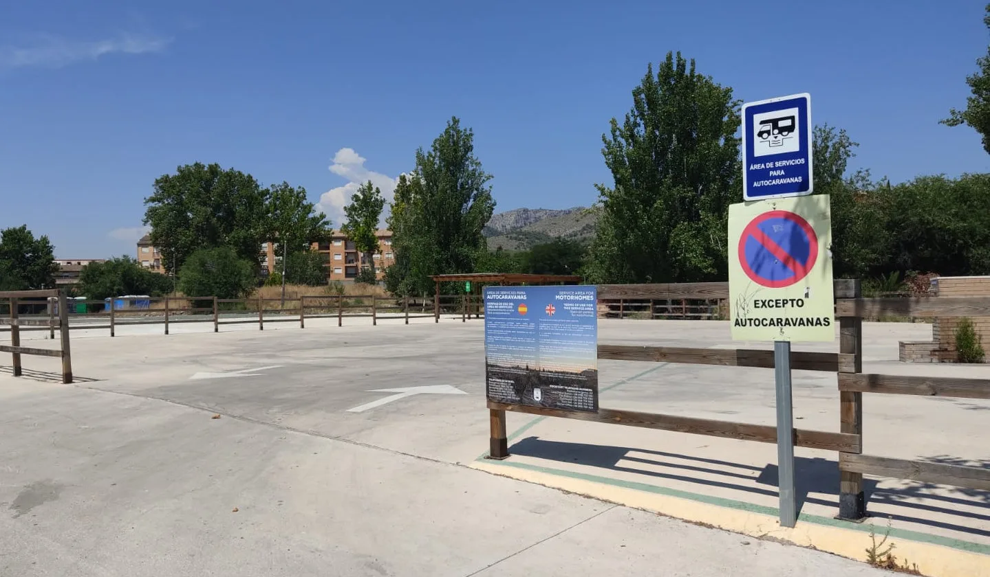 Plazas del área con la señal de área de servicio para autocaravanas y el panel informativo bilingüe
