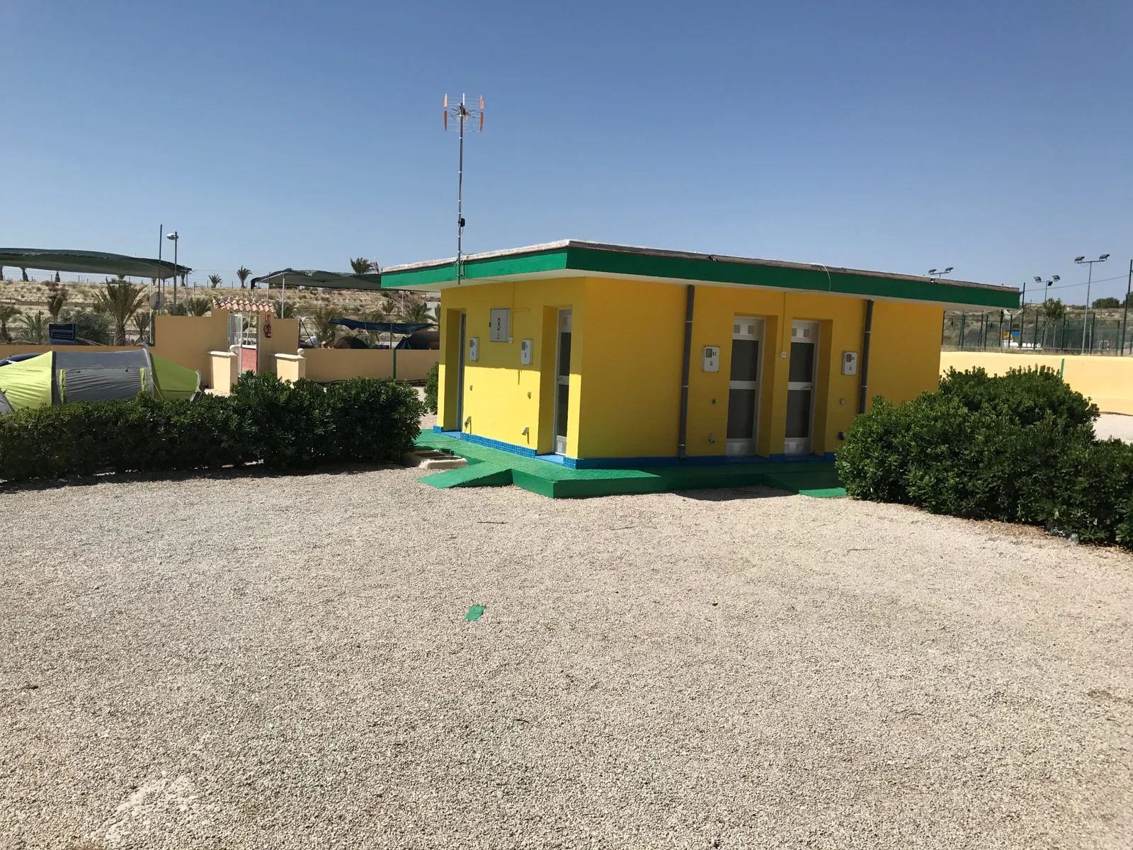 Bloque de aseos y duchas del camping, con las parcelas de grava alrededor