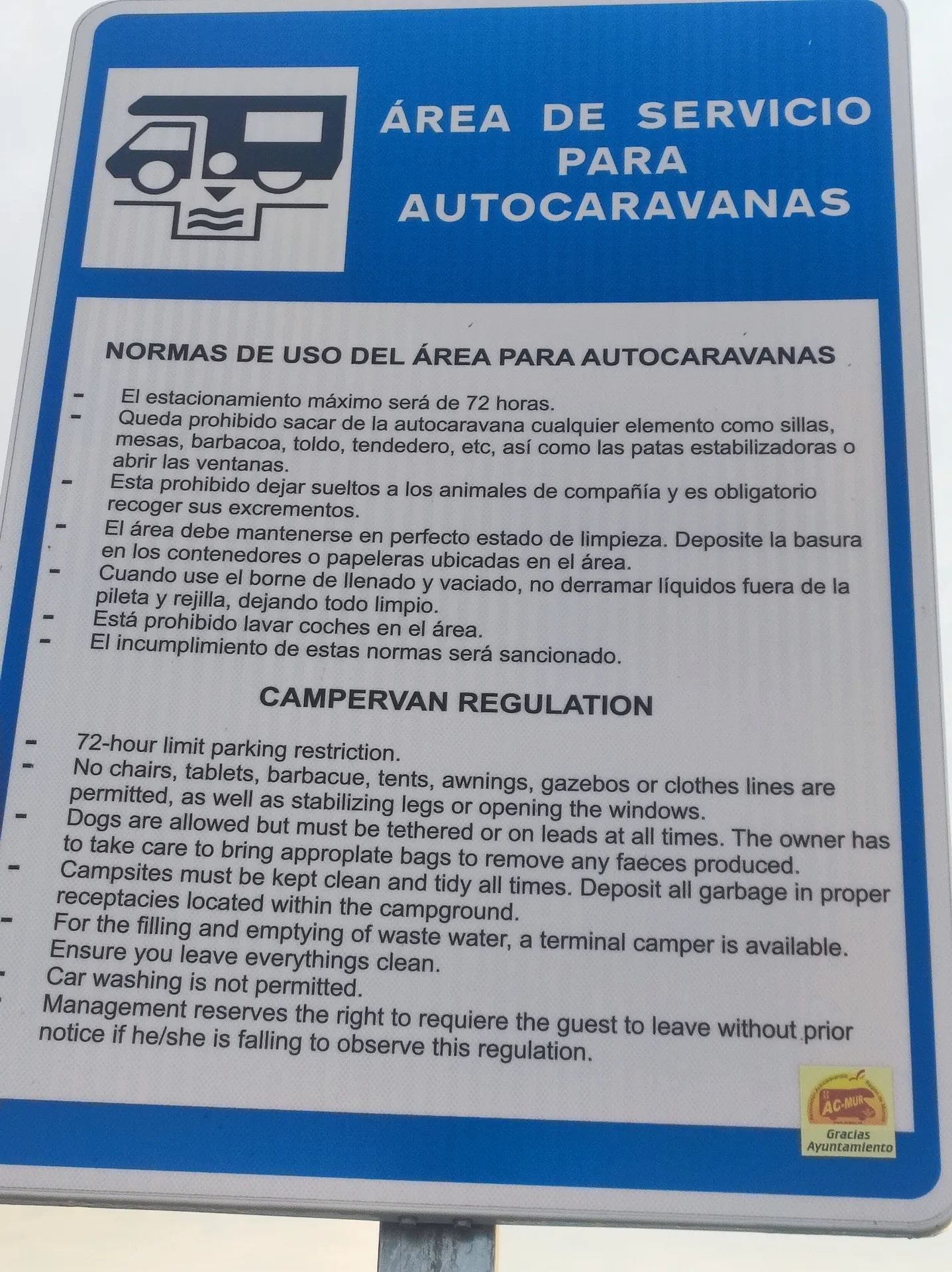 Cartel de normas de uso del área de autocaravanas, con instrucciones en español e inglés.