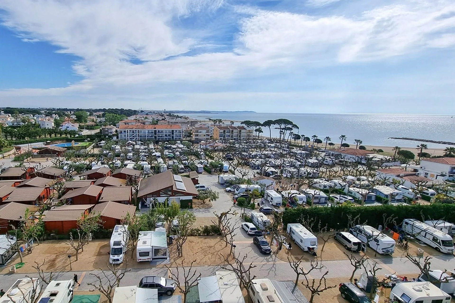Vista aérea del camping junto al mar con parcelas y caravanas.