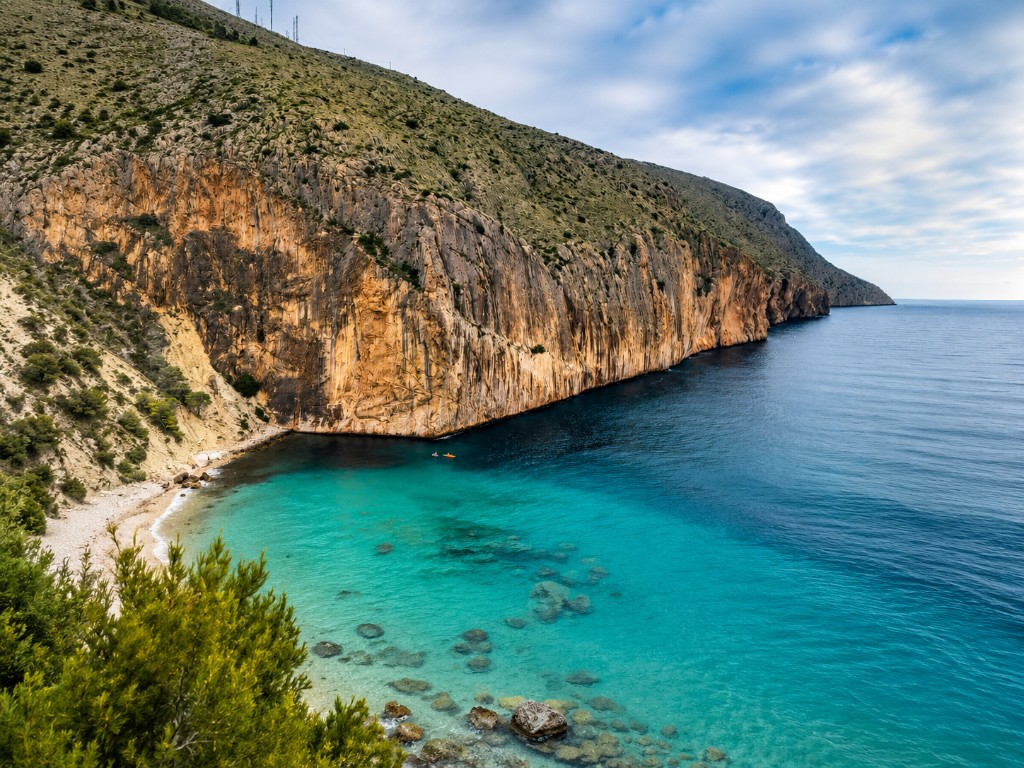 Cala de aguas turquesas con acantilado calcáreo en la costa de Alicante